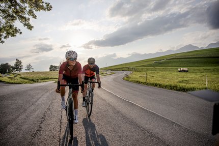 Zwei Radfahrer fahren auf einer Landstraße bei Sonnenuntergang