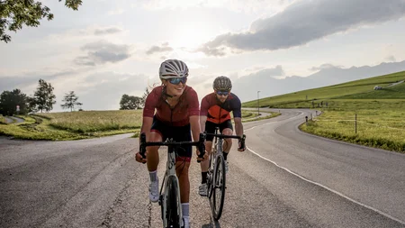 Due ciclisti pedalano su una strada di campagna al tramonto