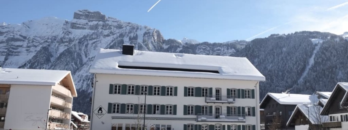 Villaggio innevato con montagne sullo sfondo e cielo azzurro limpido