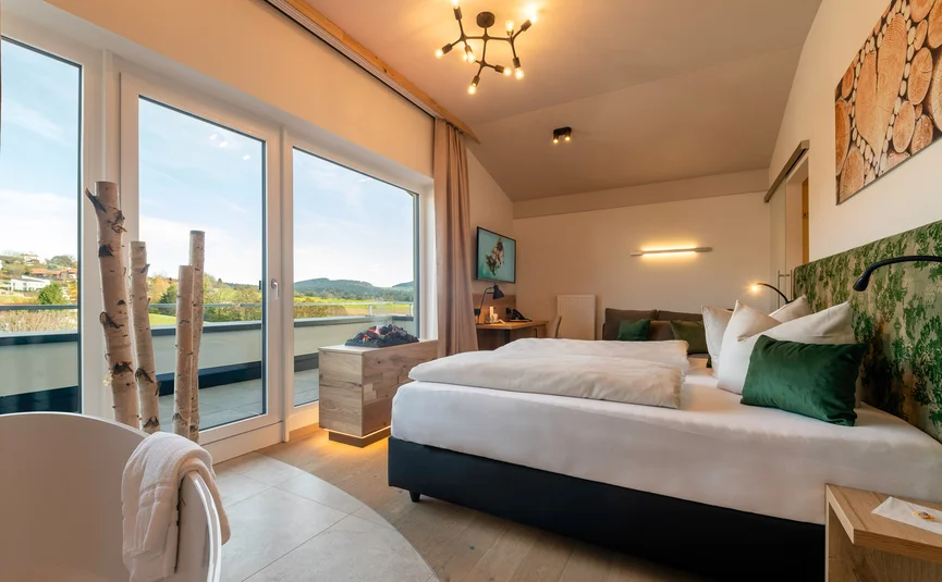 Helle Hotelzimmer mit Balkon und Blick auf grüne Hügel