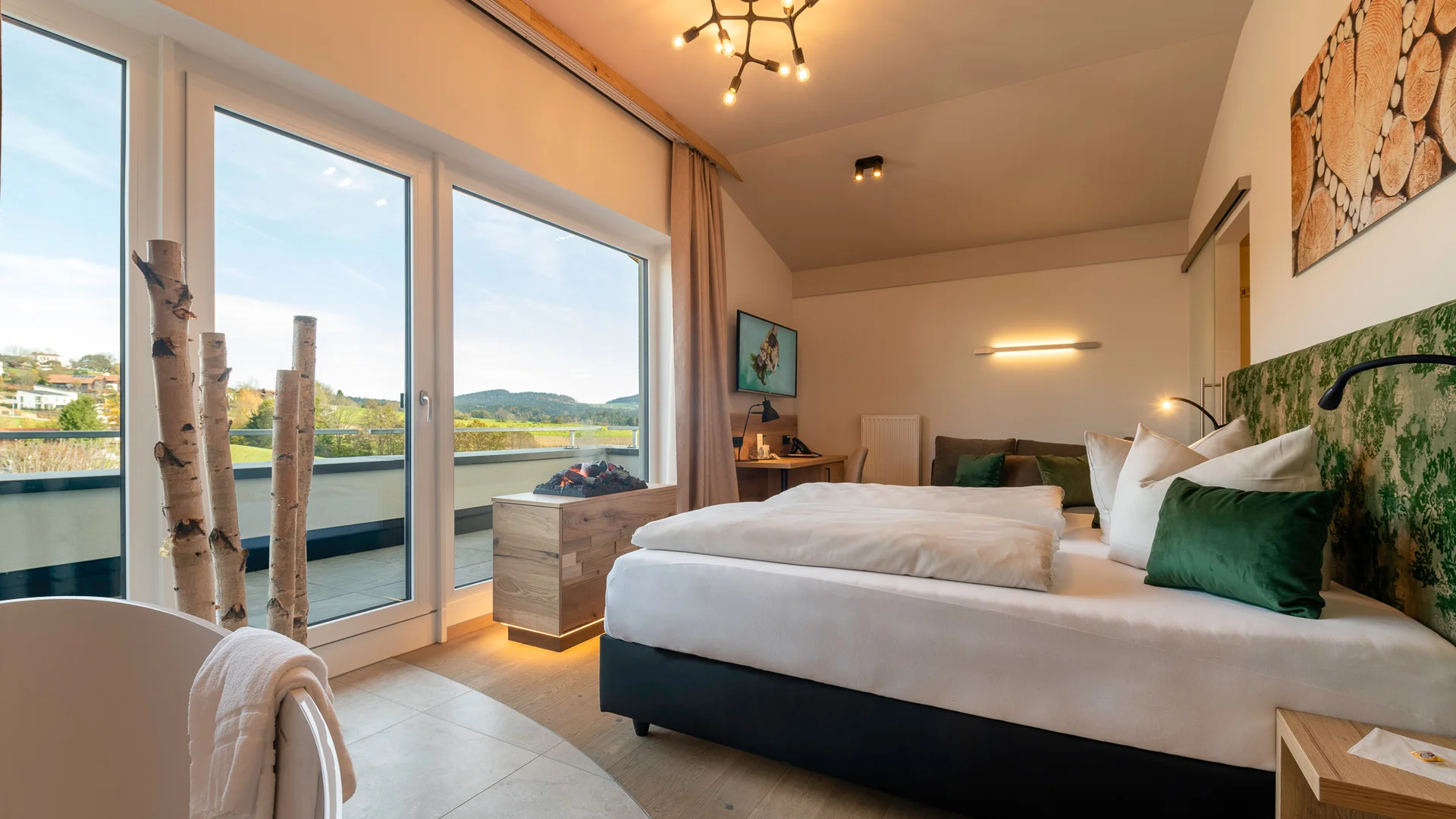 Helle Hotelzimmer mit Balkon und Blick auf grüne Hügel