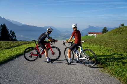 Zwei Radfahrer auf Landstraße blicken auf Berglandschaft