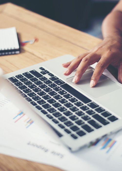 Mitgliederbereich © freepik.com Hand bedient das Trackpad eines Laptops auf einem Holztisch mit Dokumenten