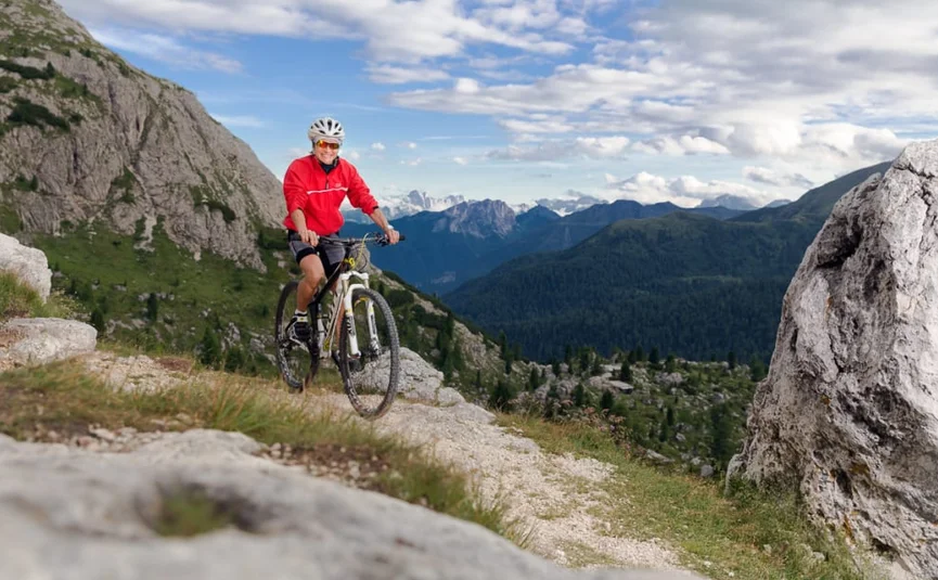Man mountainbiken op rotsachtig pad met berglandschap