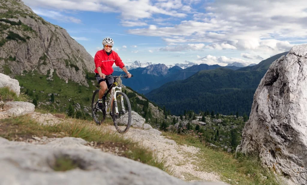 Mountainbike Experience Week Man mountainbiken op rotsachtig pad met berglandschap