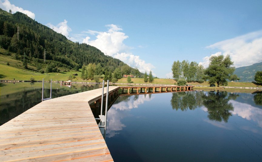 Wooden pier over calm lake reflecting trees and sky