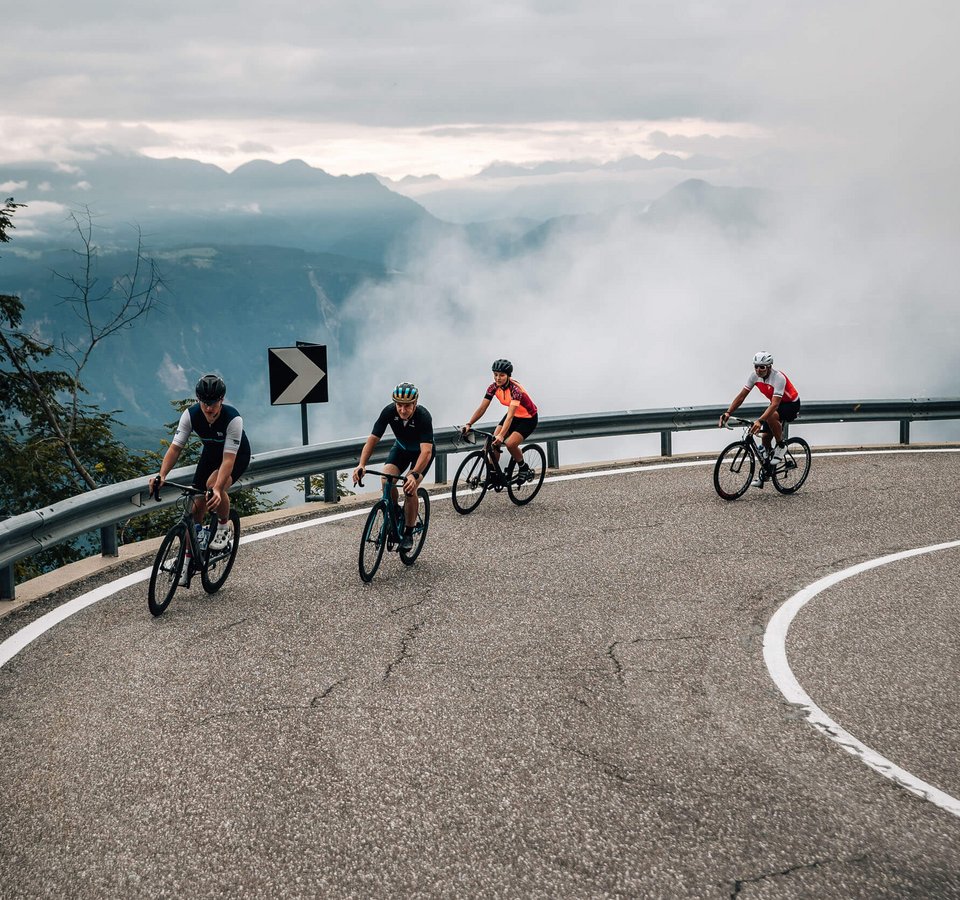 5 Rennrad-Highlights in Tramin © Jens Scheibe Vier Radfahrer fahren auf kurviger Bergstraße bei Nebel
