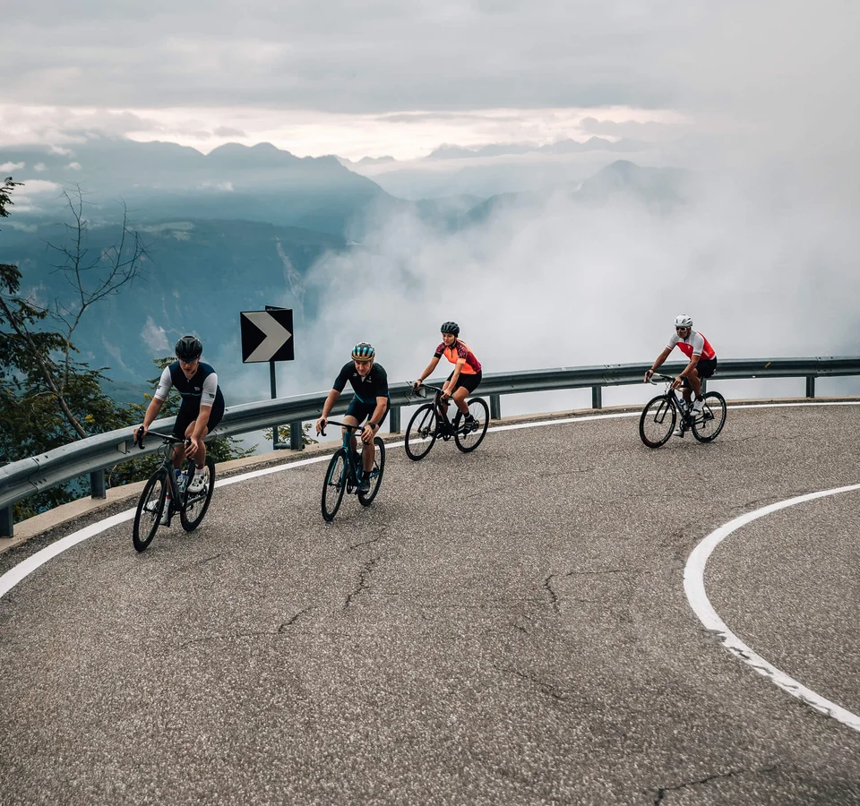 5 Rennrad-Highlights in Tramin © Jens Scheibe Vier Radfahrer fahren auf kurviger Bergstraße bei Nebel