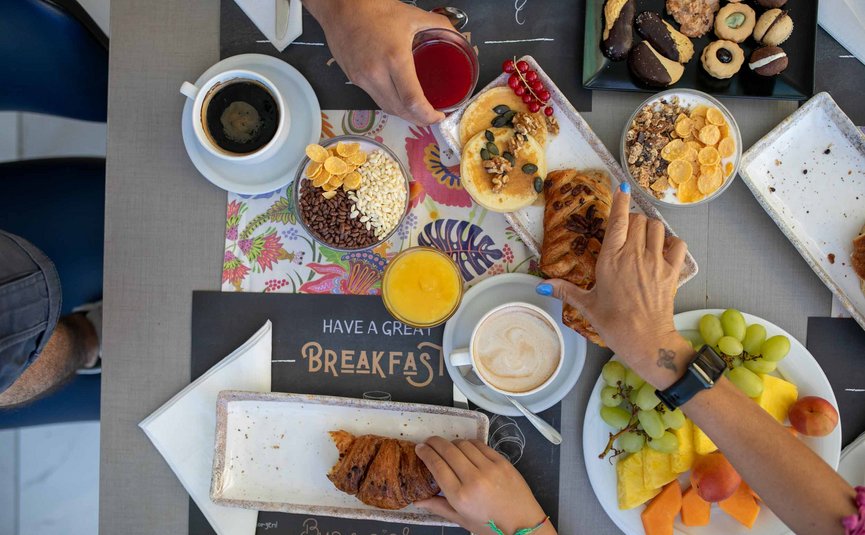 Colazione con croissant, caffè, succo, frutta e biscotti sul tavolo