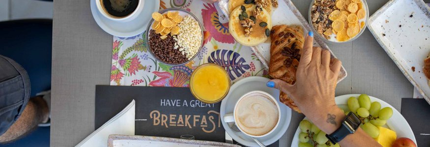 Frühstück mit Croissants, Kaffee, Saft, Obst und Keksen auf dem Tisch
