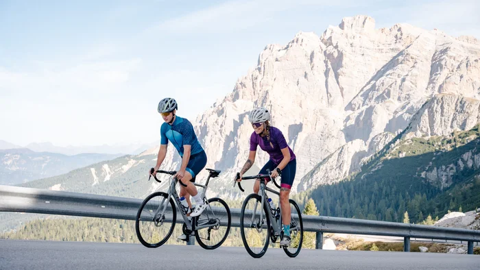 Zwei Radfahrer fahren auf Bergstraße mit Bergkulisse