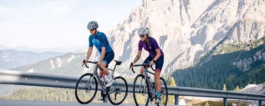 Zwei Radfahrer fahren auf Bergstraße mit Bergkulisse