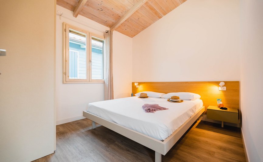 Camera luminosa con letto matrimoniale, pavimento in legno e finestra