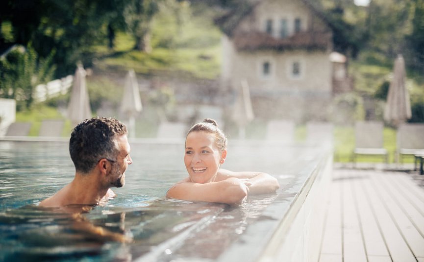 Couple relaxing in warm outdoor pool on a sunny day