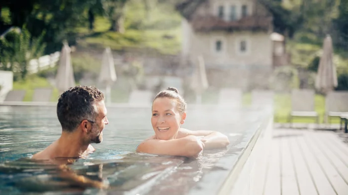 Coppia che si rilassa in piscina riscaldata all'aperto in una giornata di sole