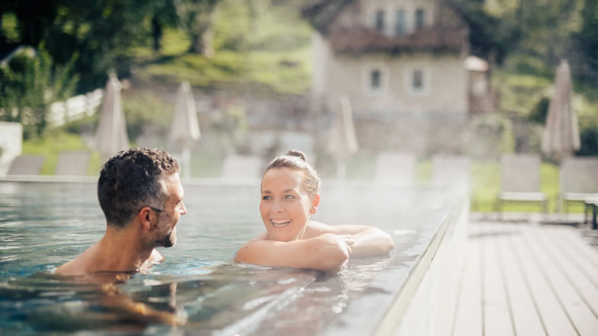 Coppia che si rilassa in piscina riscaldata all'aperto in una giornata di sole