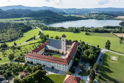 Luftaufnahme eines historischen Klosters nahe einem See und grünen Hügeln