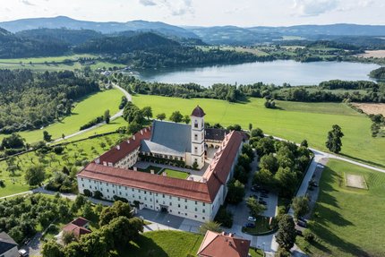 Verso il rifugio Steineren nella valle Görtschitztal © Gert Perauer Vista aerea di un monastero storico vicino a un lago e colline verdi