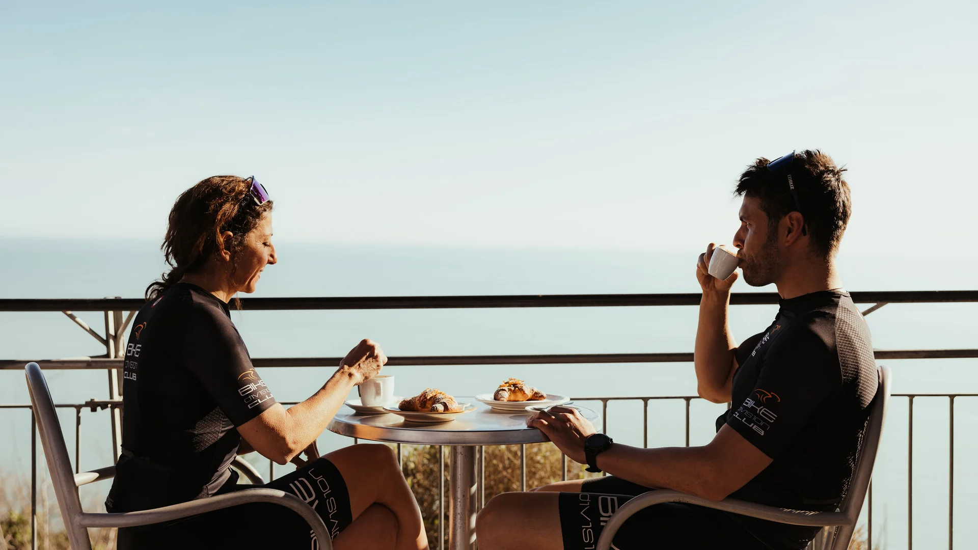 Saisonstart im Natural Village Resort © Alex Moling Zwei Radfahrer genießen Kaffee und Croissants auf Balkon mit Meerblick