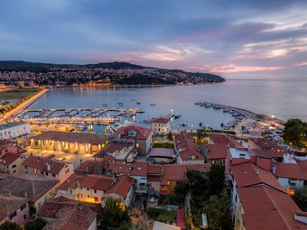 Abendlicher Blick auf Hafen und Stadt mit beleuchteten Gebäuden und Booten