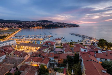 Vista serale del porto e della città con edifici e barche illuminate