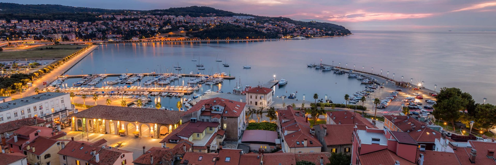 Vista serale del porto e della città con edifici e barche illuminate
