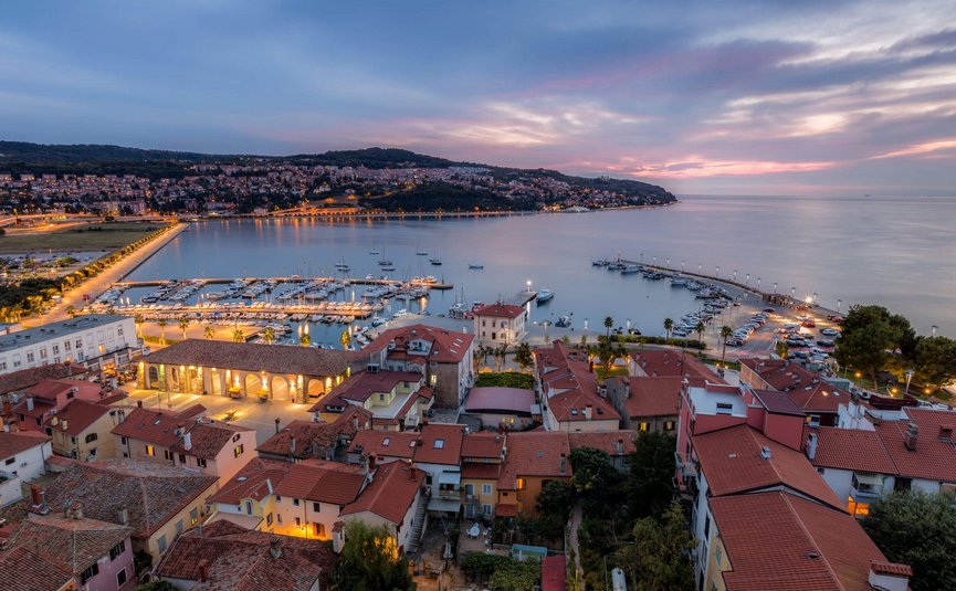 Vista serale del porto e della città con edifici e barche illuminate