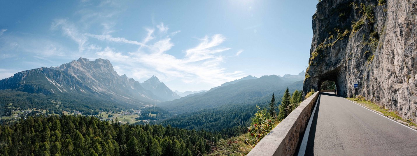 Strada di montagna con tunnel e vista sulla valle sotto cielo sereno