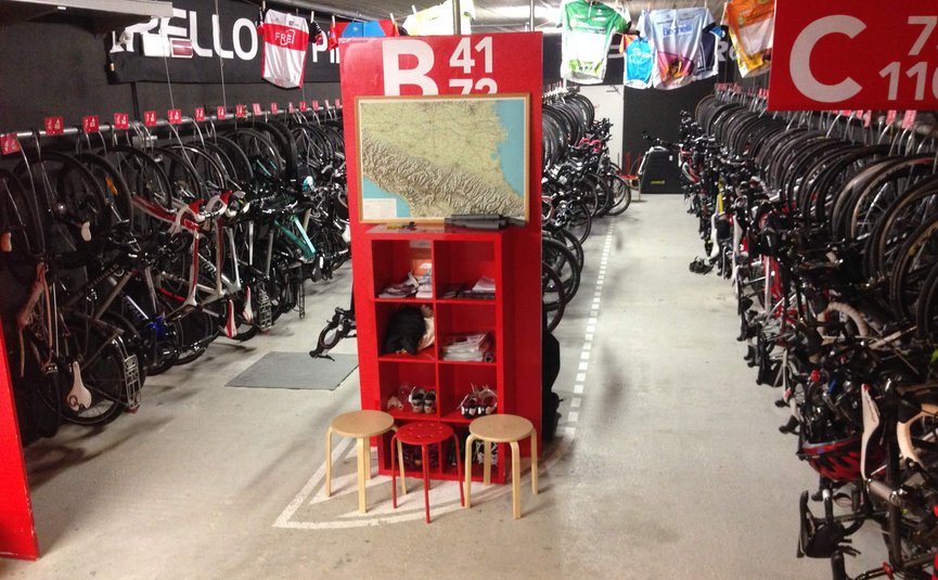 Indoor bike storage filled with many racing bicycles and stools