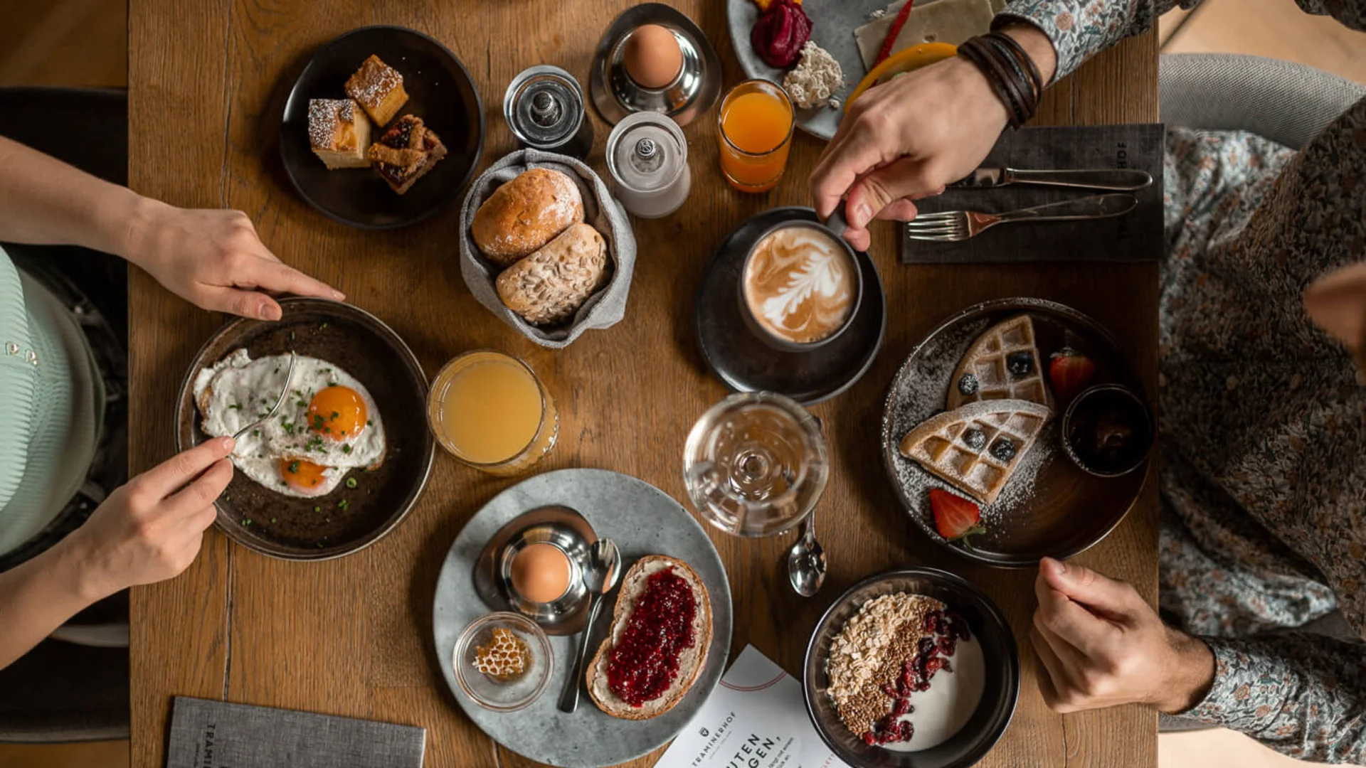 Various breakfast dishes on a wooden table with two people