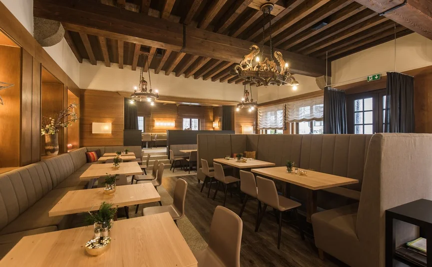 Sala ristorante accogliente con tavoli in legno e panche imbottite
