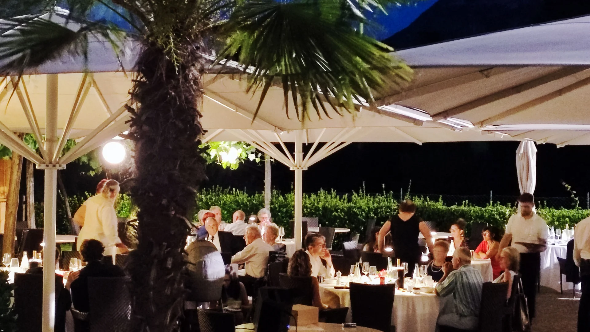 Guests seated under umbrellas in an outdoor restaurant at night