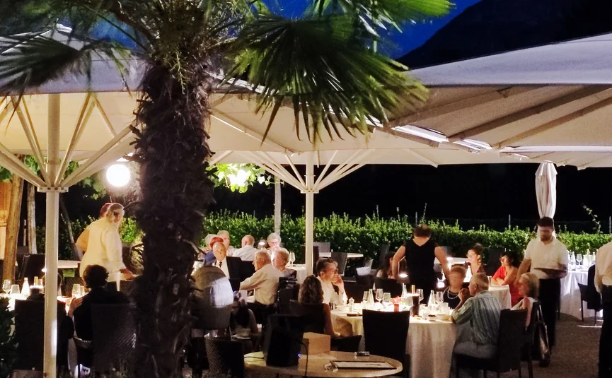 Ospiti seduti sotto ombrelloni in un ristorante all'aperto di notte