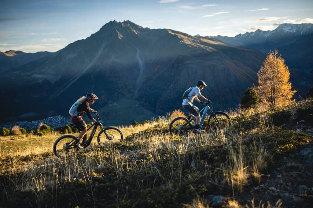 Zwei Mountainbiker fahren auf einem Bergpfad bei Sonnenuntergang