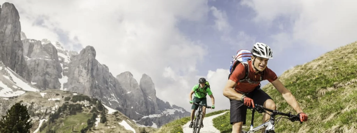 Twee fietsers op een bergpad met bergen op de achtergrond