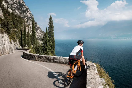 Zwischen Passstraßen, See & Dolce Vita beim Rennradurlaub am nördlichen Gardasee © Alex Moling Radfahrer auf kurviger Straße mit Blick auf See und Berge