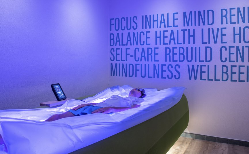 Persoon liggend in moderne ontspanningsunit met blauw licht en gezondheidswoordens