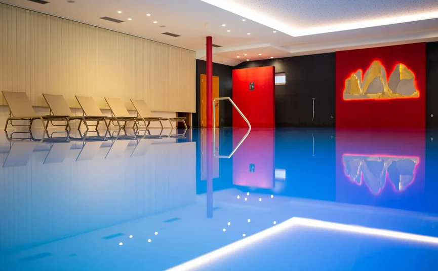 Innenpool mit Liegestühlen und roter Wanddekoration