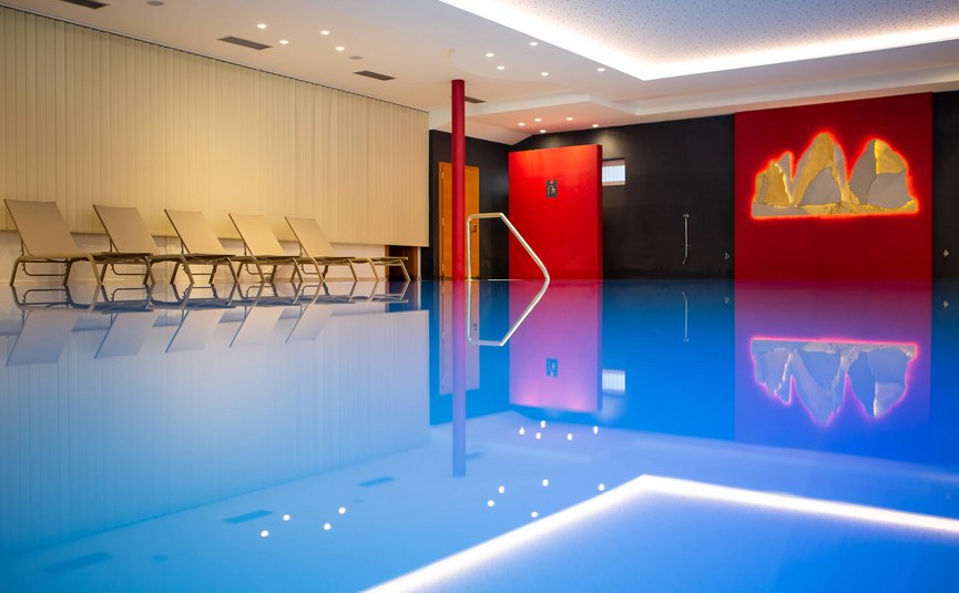 Innenpool mit Liegestühlen und roter Wanddekoration