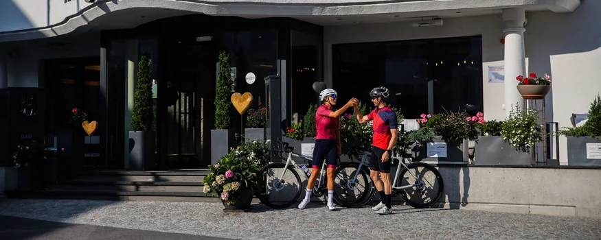 Zwei Radfahrer klatschen vor dem Central Hotel ab