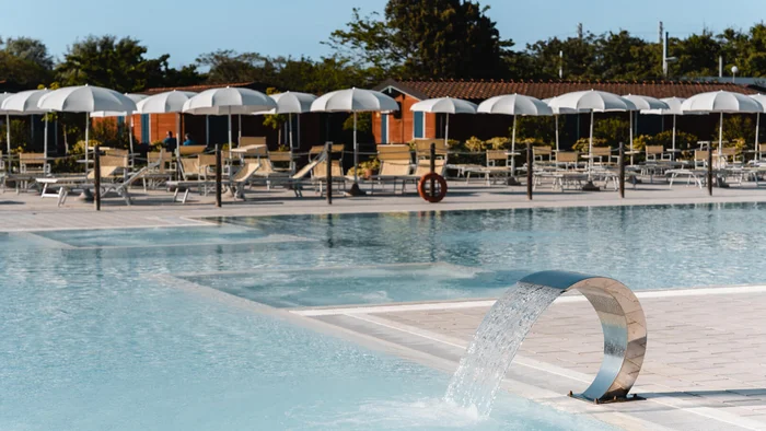 Leerer Pool mit Wasserfontäne und Sonnenschirmen am Nachmittag