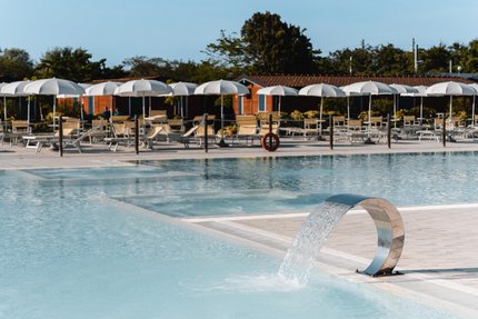 Empty pool with water fountain and sun umbrellas in the afternoon