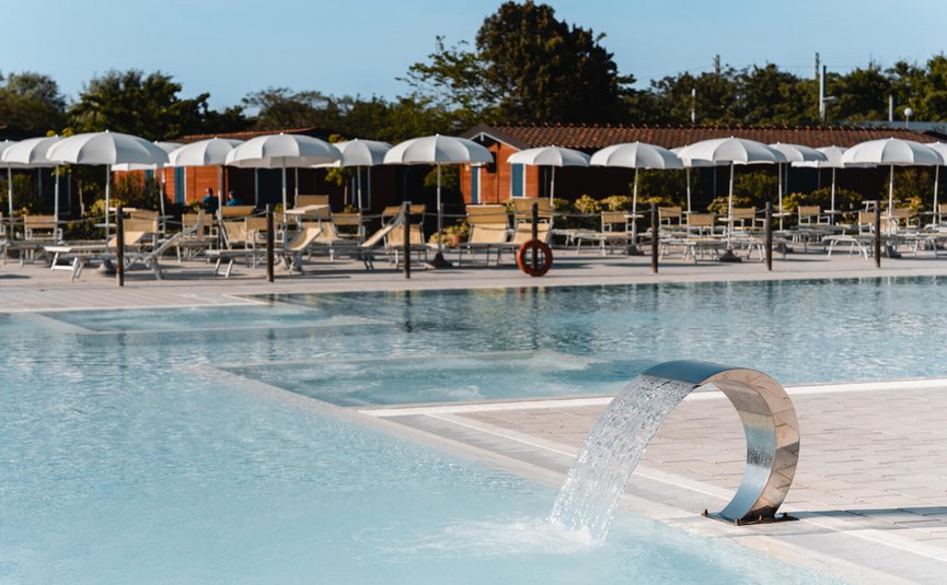 Piscina vuota con fontana d'acqua e ombrelloni al pomeriggio