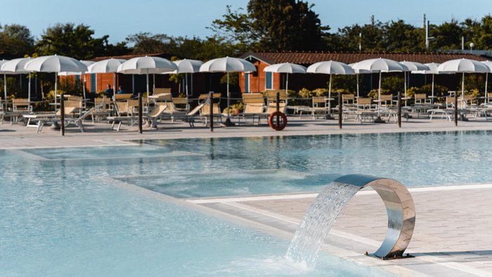 Piscina vuota con fontana d'acqua e ombrelloni al pomeriggio