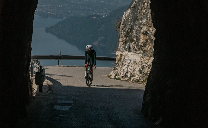 Ciclista esce dalla galleria con vista su lago e montagne