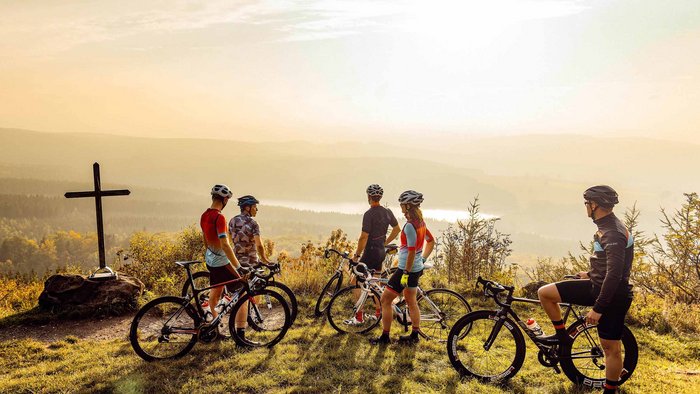 Cinque ciclisti con bici da corsa su una collina al tramonto