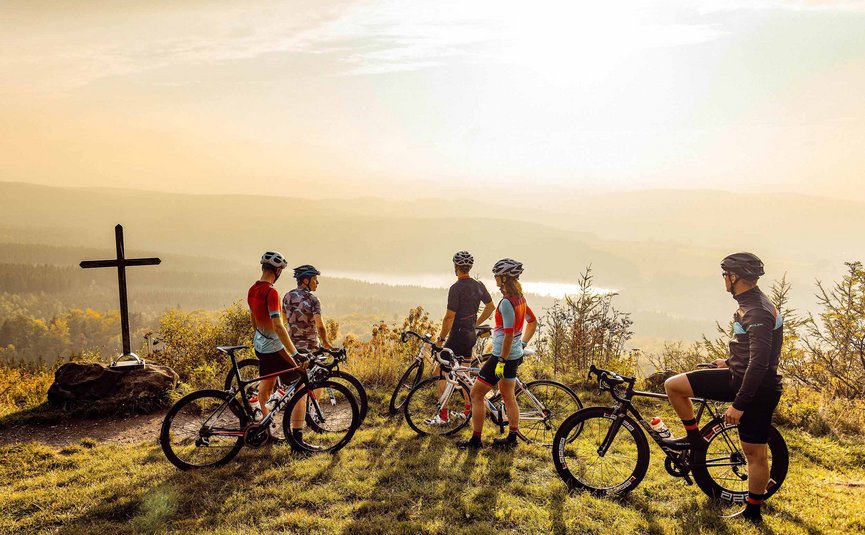 Cinque ciclisti con bici da corsa su una collina al tramonto