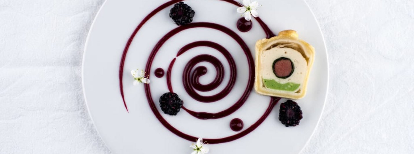 März Kurz-Auszeit Op bord geserveerd dessert met spiraalsaus, bramen, eetbare bloemen en een plak gebak