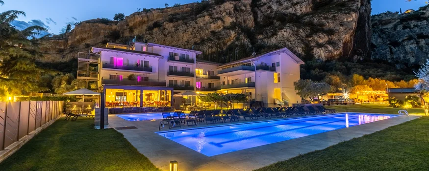 Dolce Vita tanken im AktivHotel Santa Lucia © Fabio Staropoli Beleuchtetes Hotel mit Außenpool vor Felsen bei Abenddämmerung