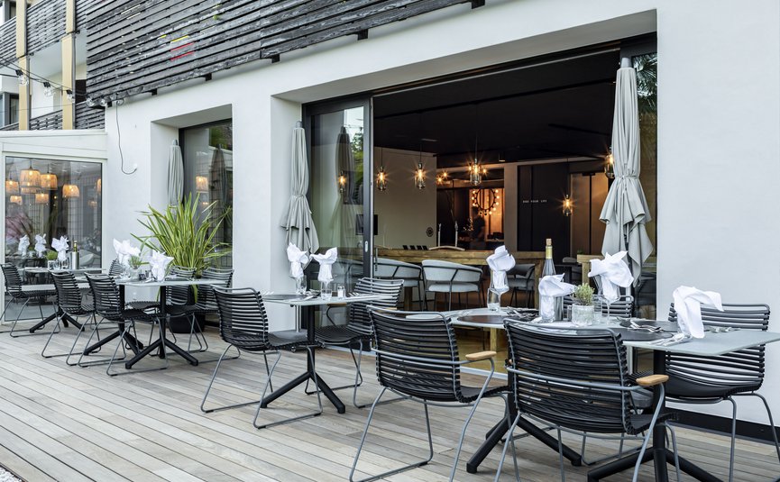 Area esterna moderna di un ristorante con tavoli apparecchiati e sedie